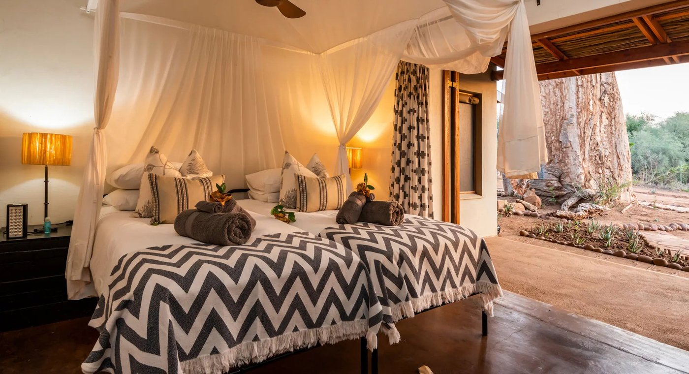 Draped four-poster bed in a stone-walled bedroom at Baobab Hill House