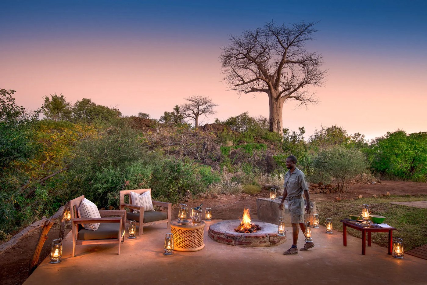 Fire pit seating at dusk beneath a baobab tree at Baobab Hill House