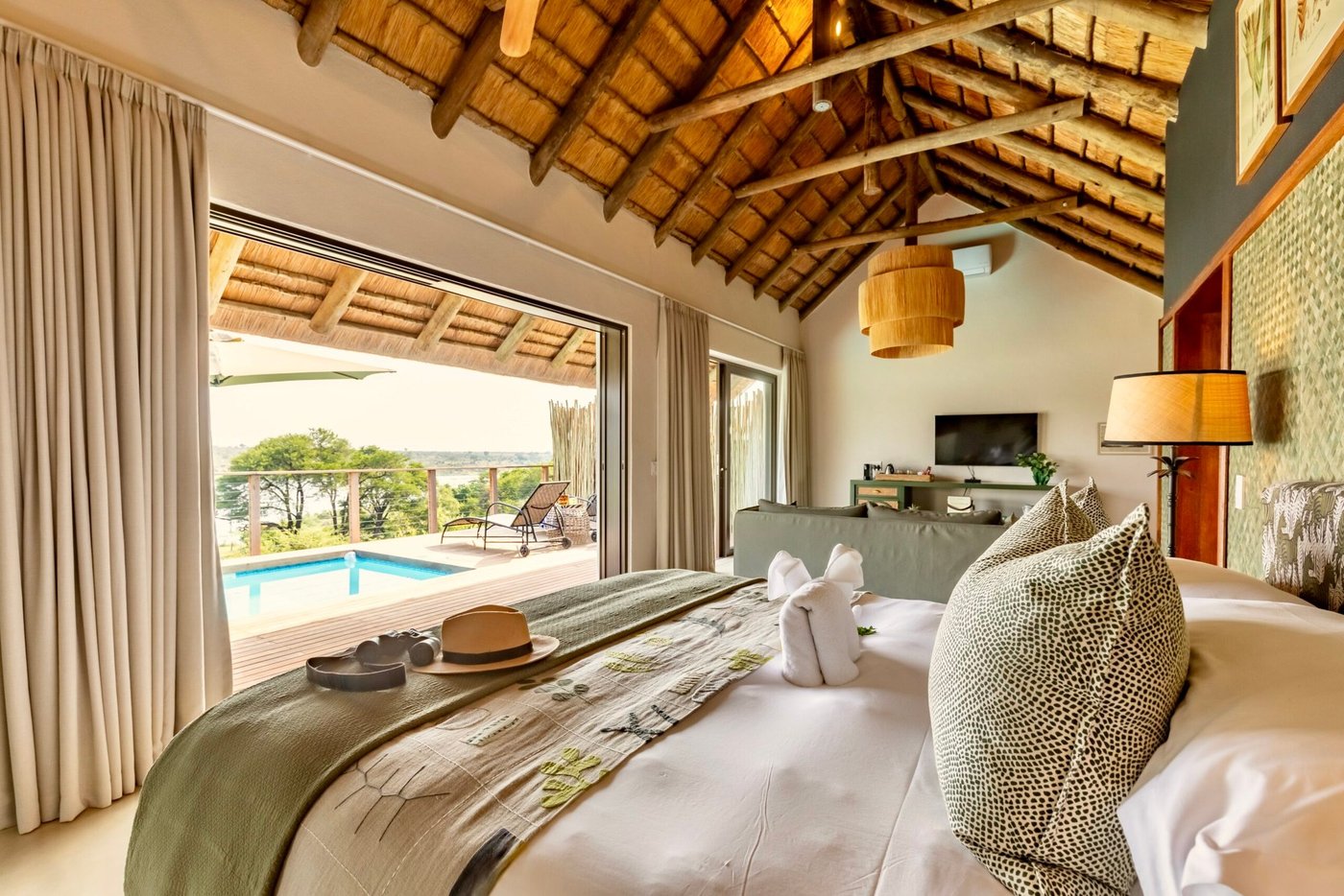 Bedroom with a freestanding bed opening onto the pool deck at Buhala Lodge