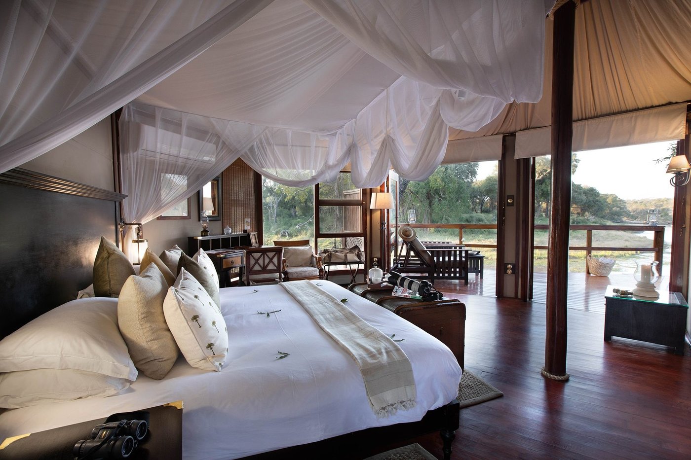 Canopied bed opening onto the deck and bush view at Hamiltons Tented Camp