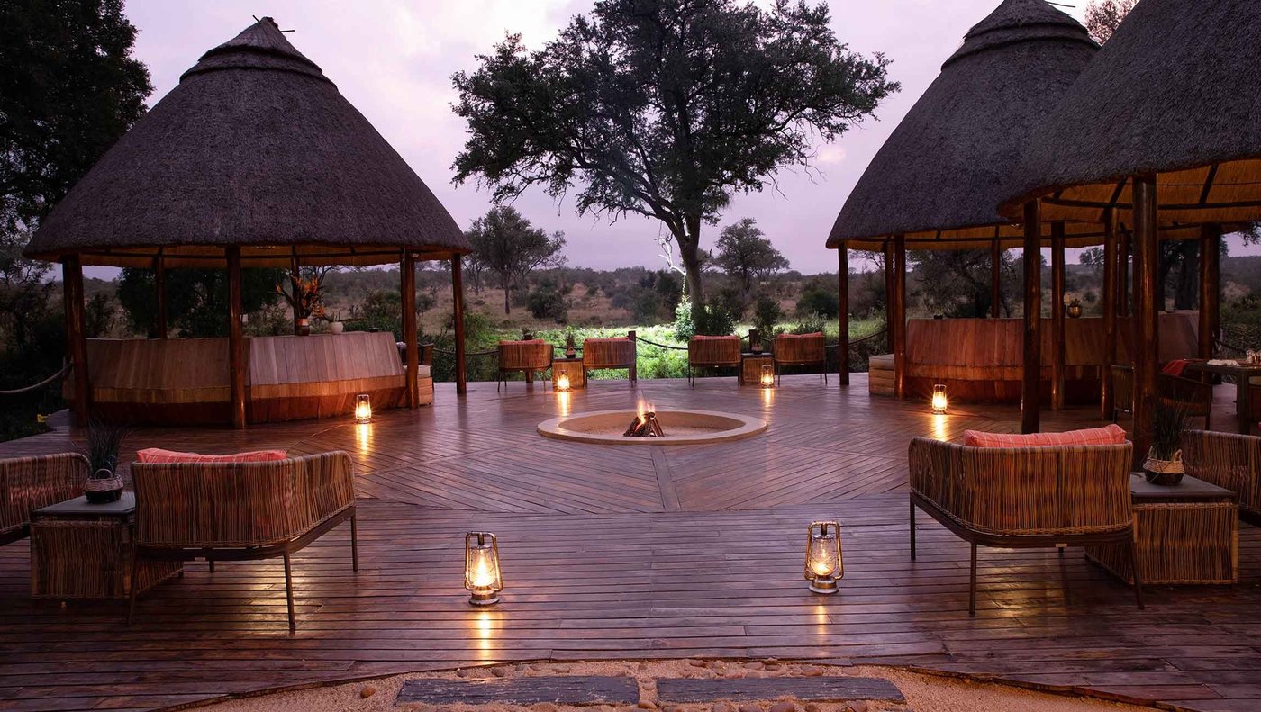 Lantern-lit lounge deck with a central fire pit at Hoyo Hoyo Safari Lodge
