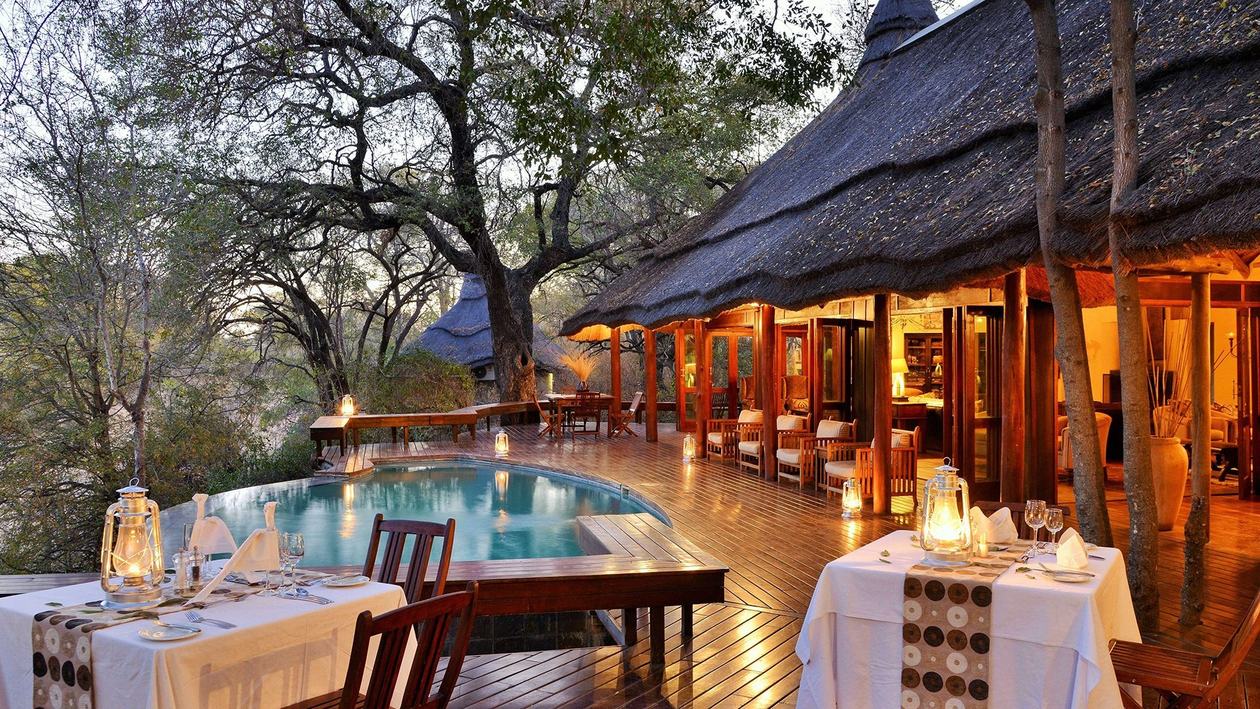 Imbali Safari Lodge poolside dining deck beneath a thatched roof in Kruger