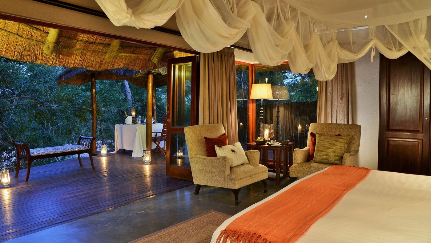 Draped four-poster bed in a thatched tented suite at Imbali Safari Lodge