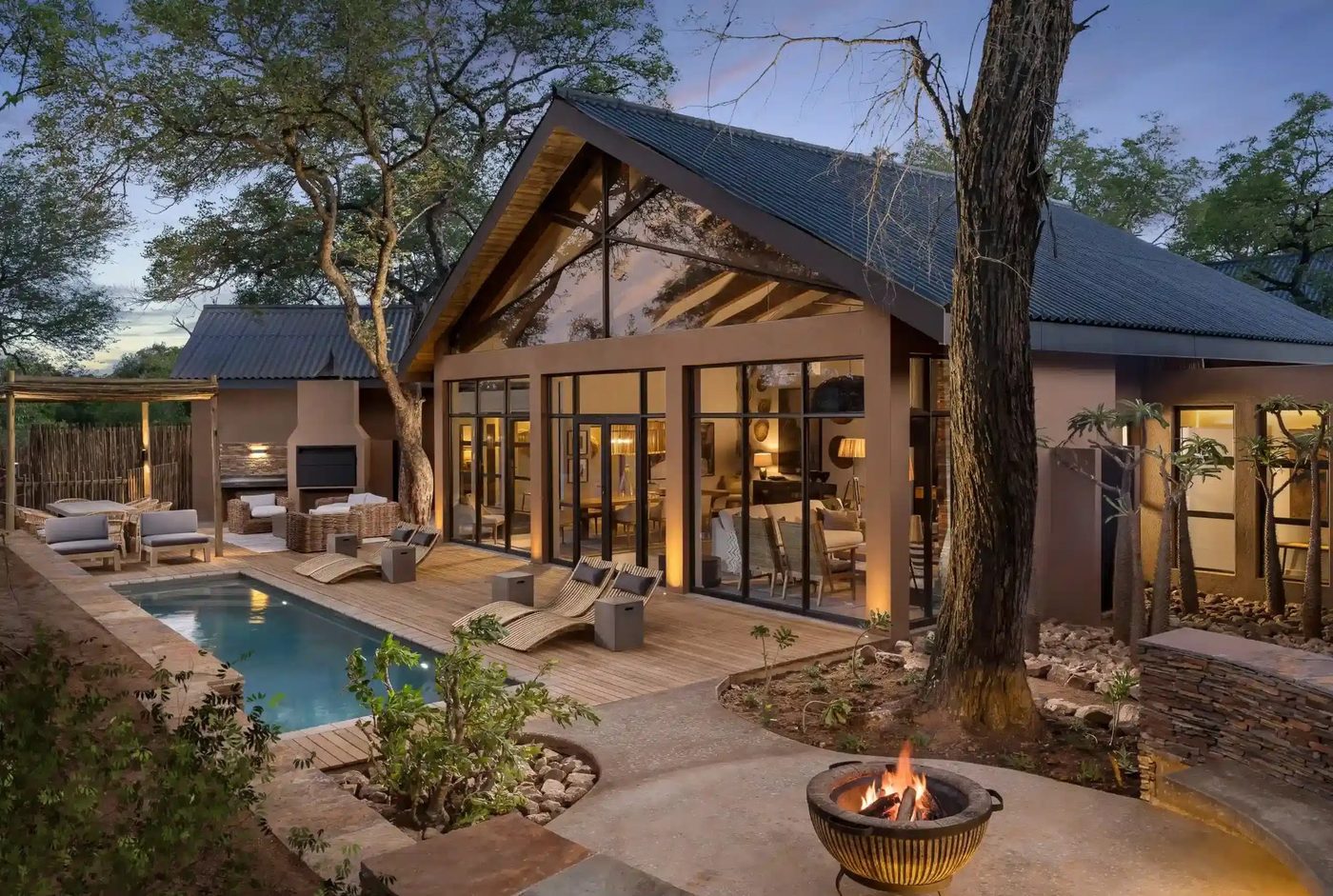 Kruger Gate Hotel thatched villa and pool lit at dusk in Kruger