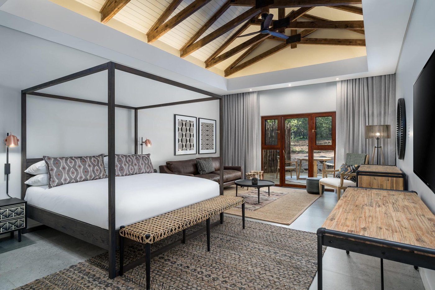 Loft-style suite with a four-poster bed and lounge area at Kruger Gate Hotel