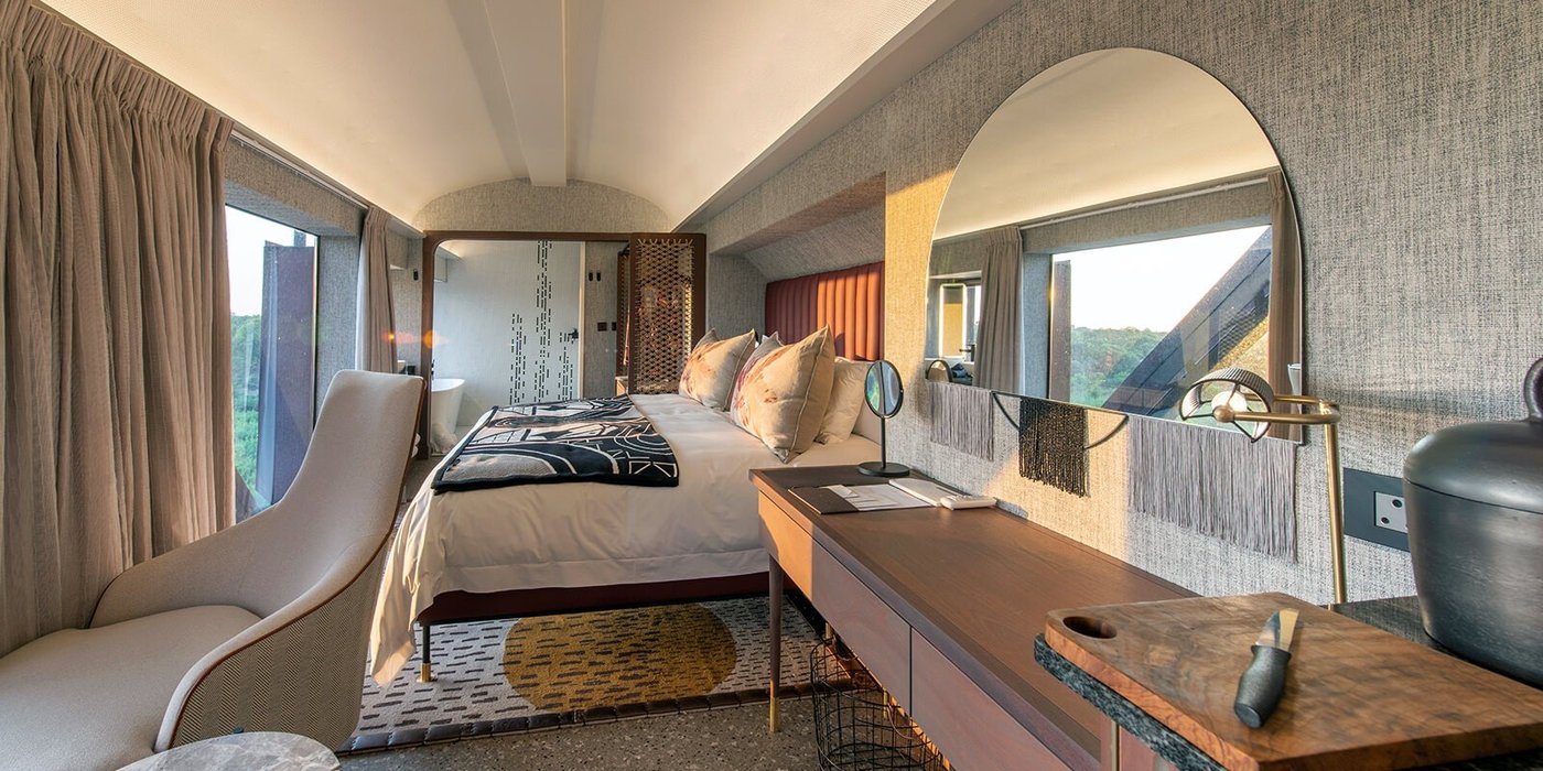 Tented suite bedroom with a daybed inside a restored train carriage at Kruger Shalati