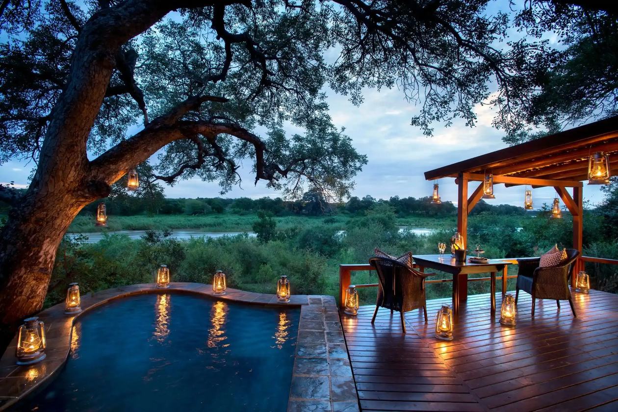 Private plunge pool deck lit by lanterns at dusk at Lion Sands Narina Lodge