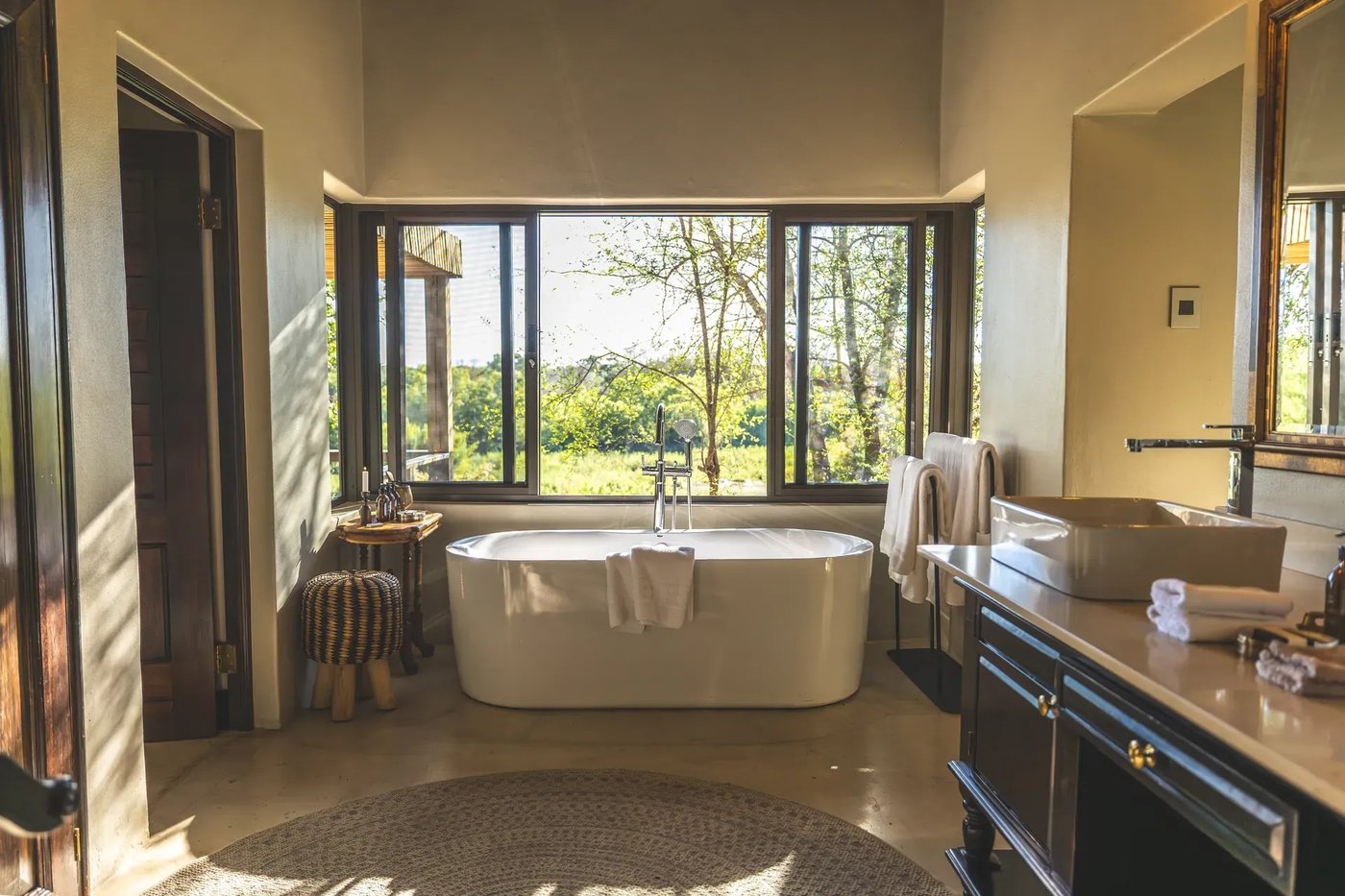 Freestanding bathtub and double vanity beside large windows at Lion Sands Tinga Lodge