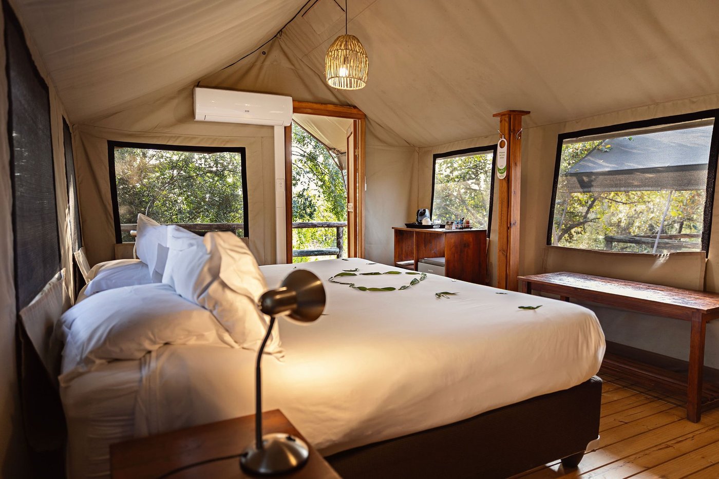 Twin tented bedroom with wooden floors and bedside lamp at Nkambeni Safari Camp