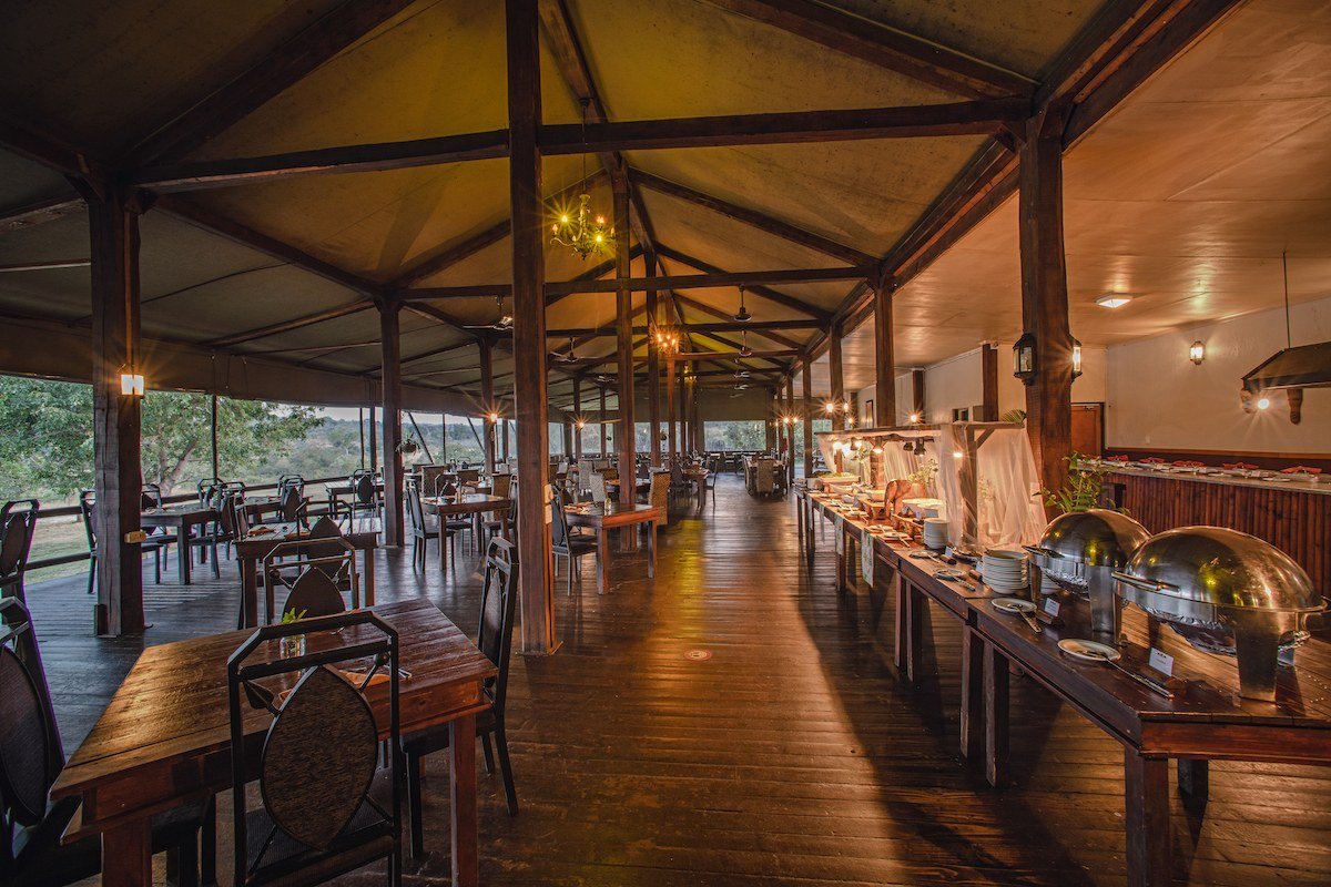 Long thatched dining hall set for a buffet at Nkambeni Safari Camp