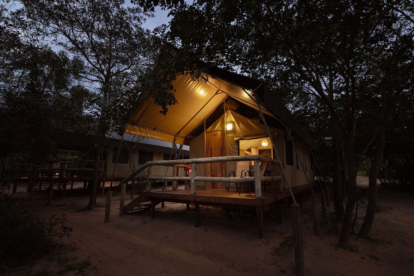 Elevated safari tent glowing among the trees at night at Nkambeni Safari Camp