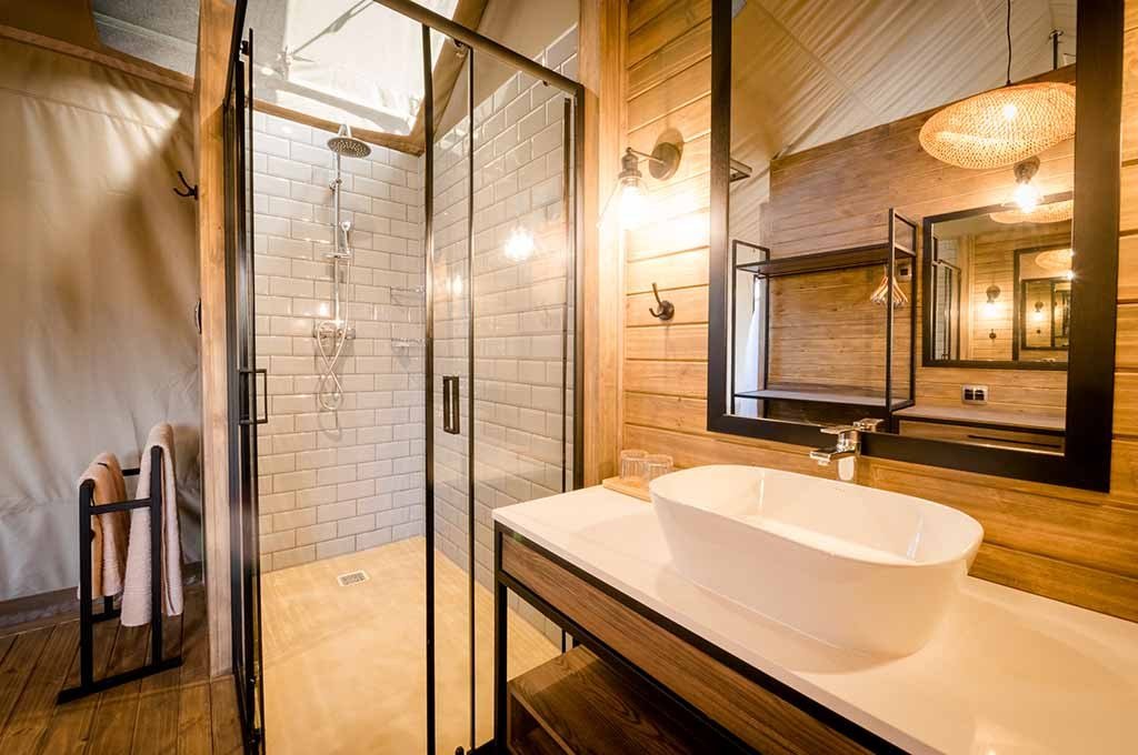 Freestanding vessel sink and glass shower in a tented bathroom at Nkuhlu Tented Camp