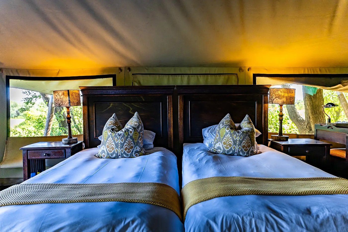 Twin beds with blue linens inside a tented suite at Plains Camp