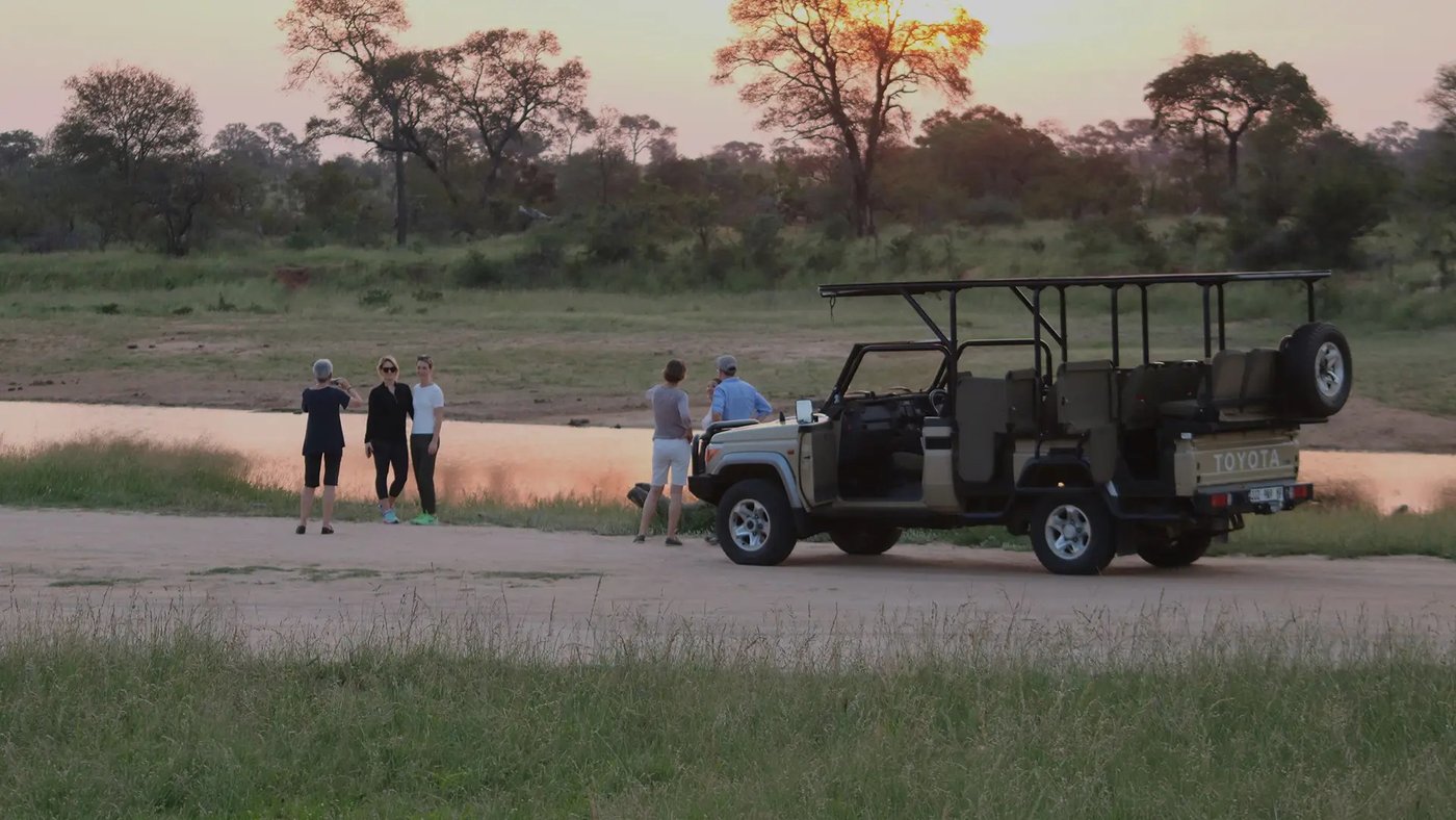 Guests on a game drive vehicle at a waterhole in the Seolo Africa concession, Kruger