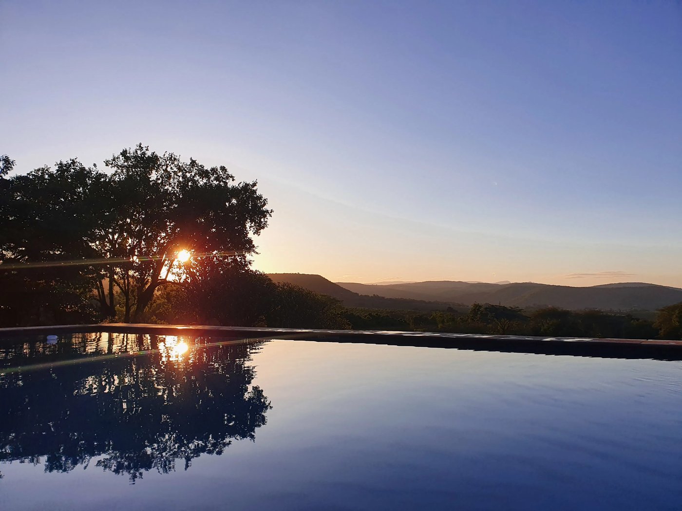 Infinity pool reflecting the sunset over the hills at Rissington Inn