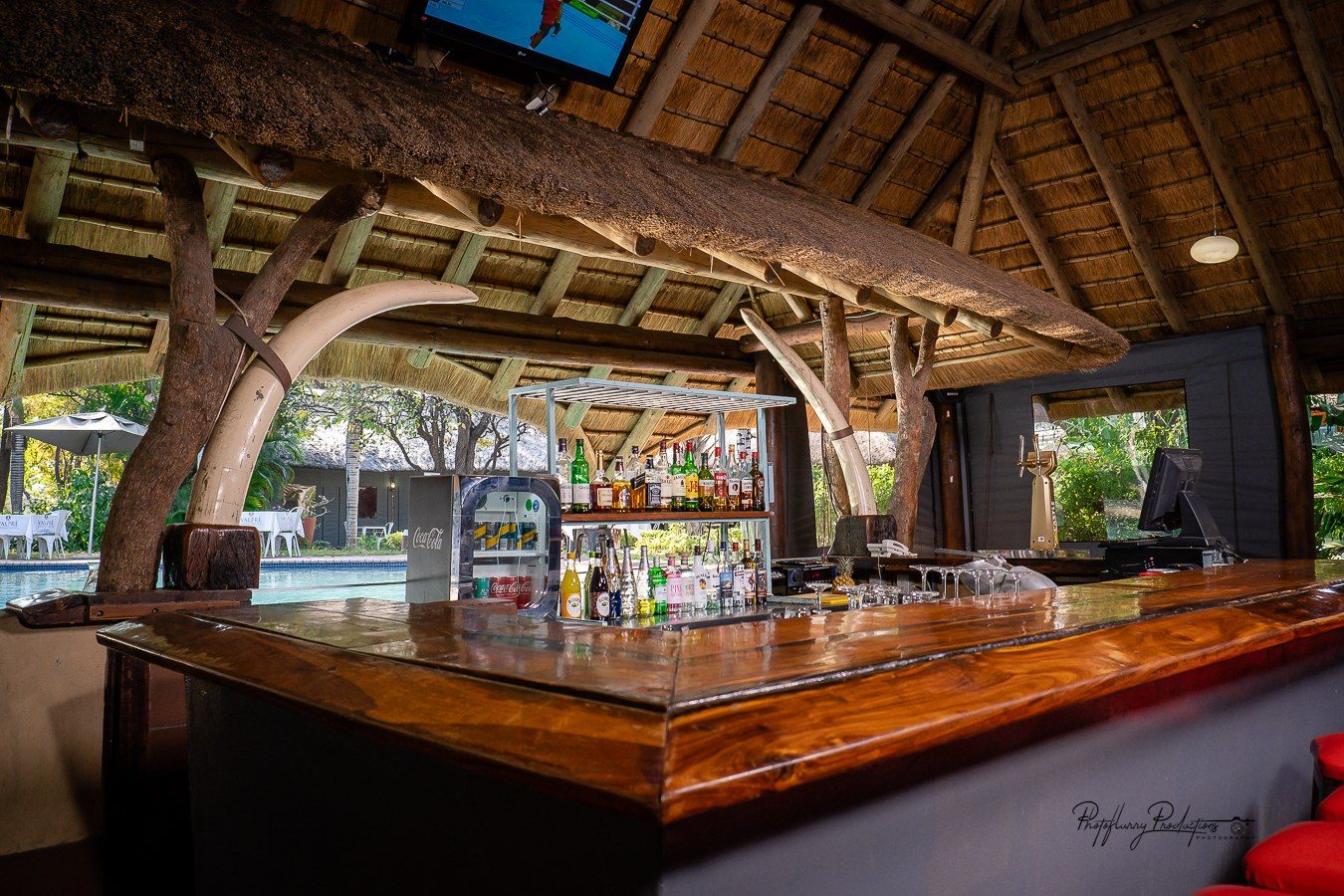 Sefapane Lodge thatched poolside bar with carved wooden beams in Kruger