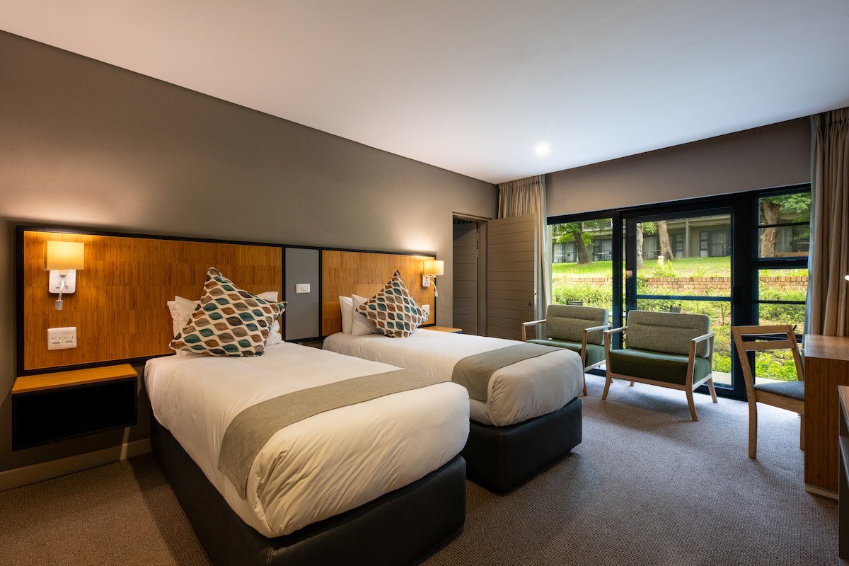 Twin room with garden-facing windows at Skukuza Safari Lodge