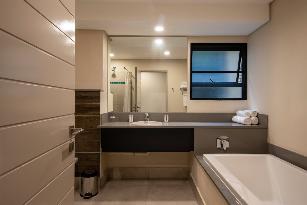 Bathroom with a soaking tub and double vanity at Skukuza Safari Lodge